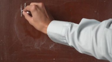Kalıplı kahverengi karatahta arka planı. Erkek el yazıları tahtada iyi bir gün geçirsin ve bir parça beyaz tebeşirle yakın çekim yap. Eğitici ve yaratıcı içerik, okul kavramı.