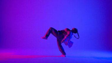 Stüdyoda pembe ve mavi neon arka planda dans eden çekici kadın. Modern dinamik ve enerjik dans koreografisi. Tam boy. Yaratıcı içerik, tanıtım videosu veya reklam.