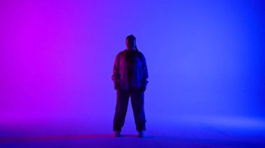 Stüdyoda pembe ve mavi neon arka planda dans eden çekici kadın. Modern dinamik ve enerjik dans koreografisi. Tam boy. Yaratıcı içerik, tanıtım videosu veya reklam.