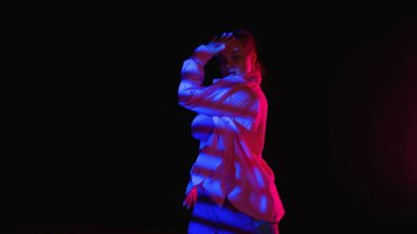 Çekici bir kadın, bir stüdyoda siyah izole edilmiş arka planda caz funk dansı yapıyor. Yeşil spot ışıkları, çizgili düşen gölge enerjik dans koreografisi. Yaratıcı içerik, tanıtım videosu veya reklam.