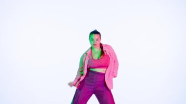 Stüdyoda izole edilmiş beyaz arka planda dans eden çekici kadın. Yeşil ve kırmızı spot ışıkları, enerjik dans koreografisi. Orta boy. Yaratıcı içerik, tanıtım videosu veya reklam.