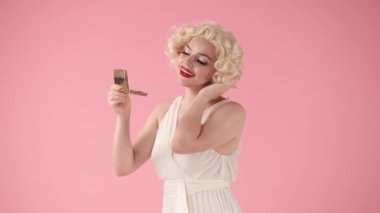 Marilyn Monroe 'nun aynadaki yansımasına hayran genç bir kadın. Bir kadın yansımasına gülümser ve hava öpücüğü gönderir. Beyaz peruklu, beyaz elbiseli, parlak makyajlı bir kadın stüdyoda...