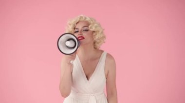 Bir kadın megafona konuşur ve işaret eder, davet eder. Marilyn Monroe 'nun stüdyodaki pembe arka plandaki görüntüsü.
