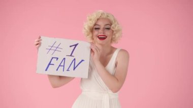 Neşeli bir kadın bir numaralı hayranı olan bir pankartı kaldırıyor. Stüdyodaki Marilyn Monroe 'ya benzeyen bir kadın.