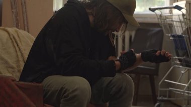 Terk edilmiş bir binanın odasında oturan evsiz zavallı adam. Dişleriyle turnikeyi tutuyor ve damarına yasadışı bir madde enjekte ediyor. Evsizlik ve yoksulluk, işsizlik, kriz