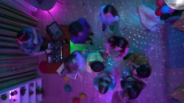 一群青少年带着迪斯科舞会在装饰过的宴会厅里跳舞 一个男人在Dj控制台上混合着音乐 霓虹灯 顶部视图 高中和大学教育 广告或创意内容 — 图库视频影像