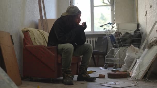 버려진 건물의 노숙자 가난한 남자는 자신의 빈약한 소지품으로 관절을 밝히고 — 비디오