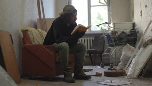 Chudák Bezdomovec Sedící Opuštěné Budově Plné Jeho Skrovných Věcí Čte — Stock video