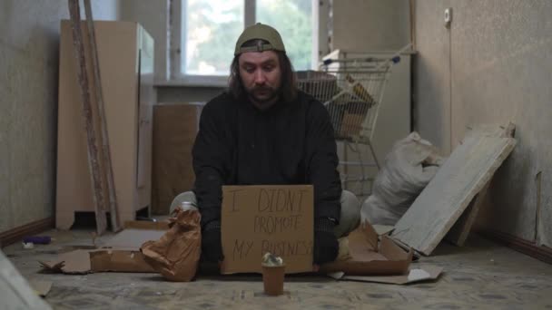 Homeless Poor Man Sitting Room Abandoned Building Holding Piece Cardboard — Stock Video