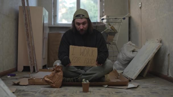 노숙자 가난한 남자는 항아리와 버려진 건물의 마분지 조각을 있습니다 음식에 — 비디오