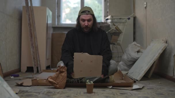 Άστεγος Άνθρωπος Κάθεται Ένα Δωμάτιο Ενός Εγκαταλελειμμένου Κτιρίου Κρατάει Ένα — Αρχείο Βίντεο