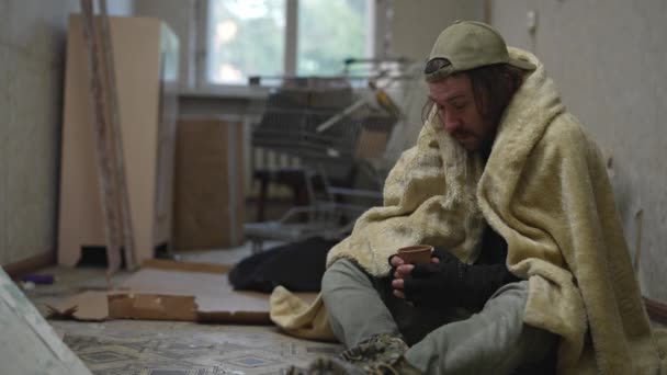 Bezdomny Biedak Siedzi Opuszczonym Budynku Próbuje Ogrzać Się Pod Kocem — Wideo stockowe