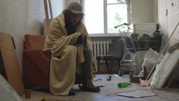Bezdomny Biedak Pokryty Kocem Siedzący Opuszczonym Budynku Wypełnionym Swoimi Skromnymi — Wideo stockowe