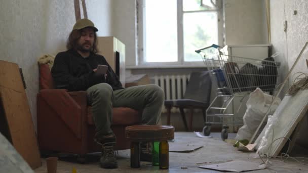Άστεγος Άνθρωπος Κάθεται Ένα Δωμάτιο Ενός Εγκαταλελειμμένου Κτιρίου Παίρνει Ένα — Αρχείο Βίντεο