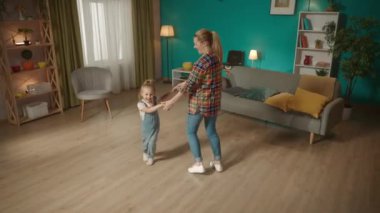 Küçük kız ve sevgili anne oturma odasında el ele tutuşup dans ediyorlar. Aile birlikte eğleniyor, olumlu duyguların tadını çıkarıyor. Aile ilişkileri kavramı