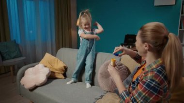 Anne ve tatlı küçük kızı akşamları oturma odasındaki kanepede oturarak vakit geçiriyorlar. Annem sabun köpüğü üflüyor ve küçük anaokulu kızı onları yakalıyor ve patlatıyor. Yavaş çekim