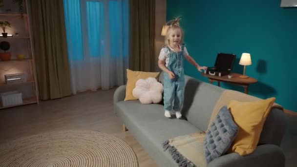 Kleines Mädchen Springt Auf Die Couch Wohnzimmer Lacht Und Klatscht — Stockvideo