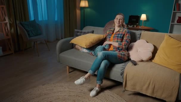 週末は自宅で 女性と娘がテレビを見ていて 笑っている ママと娘は リビングルームのソファーに座って エンターテイメントプログラム 漫画を見ています スローダウン — ストック動画