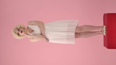 Marilyn Monroe 'nun görünüşünde bir kadın, rüyasında bir şey düşünüyor, parmaklarını yalayarak dudaklarına bastırıyor, bir fikir var. Stüdyoda kırmızı bir kaide üzerinde duran bir kadın.