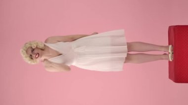 Kadın agresif konuşuyor, bağırıyor, işaret parmağını sana doğrultuyor, seni suçluyor. Marilyn Monroe 'nun görüntüsündeki kızgın, hayal kırıklığına uğramış kadın pembe bir stüdyoda kırmızı bir kaidede dikiliyor.