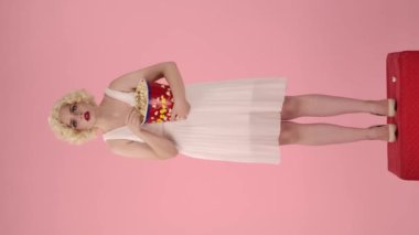 Bir kadın film izlerken büyük bir kovadan patlamış mısır yiyor. Kadın korkudan titriyor. Korku filmi. Marilyn Monroe rolünde bir kadın pembe arka planda stüdyoda boy gösteriyor. Dikey