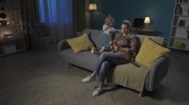 Genç bir kadın, bir anne, akıllı telefonuna dalmış ve kızına dikkat etmiyor. Anne ve kızı akşamları oturma odasında kanepede oturuyorlar. Ebeveynlik sorunları. SorunlarName