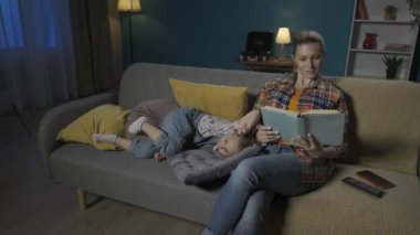 Küçük kız oturma odasında annesinin yanındaki kanepede yatarken bir şey söylüyor. Küçük kız, tutkulu bir şekilde HDR kitabı okuyan annesinin dikkatini çekmeye çalışıyor.