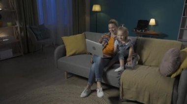 Mutlu, genç bir anne ve genç bir kız kanepede oturup videolar, dizüstü bilgisayarda çizgi filmler izliyorlar. Anne ve kızı öpüşüyor, sarılıyor, akşamları birlikte oturma odasında vakit geçiriyorlar.