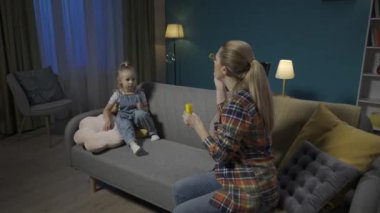 Anne ve tatlı küçük kızı akşamları oturma odasındaki kanepede oturarak vakit geçiriyorlar. Annem sabun köpüğü üflüyor ve küçük anaokulu kızı onları yakalıyor ve patlatıyor. Aile