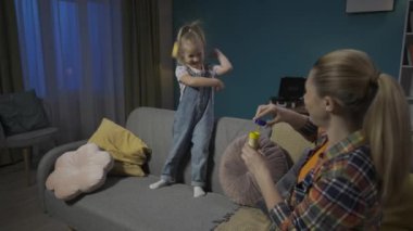 Anne ve tatlı küçük kızı akşamları oturma odasındaki kanepede oturarak vakit geçiriyorlar. Annem sabun köpüğü üflüyor ve küçük anaokulu kızı onları yakalıyor ve patlatıyor. Yavaş çekim