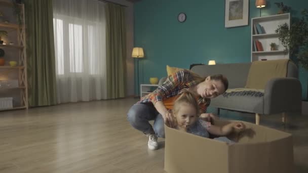 妈妈和她的小女儿玩得很开心 快乐的年轻妈妈蹲在纸盒旁边 她的小女儿坐在纸盒里吃棒棒糖 家庭关系概念Hdr Bt2020 Hlg材料 — 图库视频影像