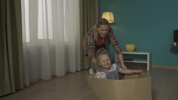 Mãe Filha Divertirem Mamãe Está Empurrando Uma Caixa Papelão Chão — Vídeo de Stock