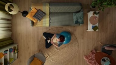 Yukarıdaki karede, hamile bir kadın spor topuna yaslanmış yatıyor. Annelik fitness kursuna gidiyor. Gözlerini kapayarak gülümsüyor ve rahatlıyor. Aileye yeni birinin katılmasını bekliyorum..