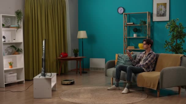똑똑한 창조적인 아파트에서 남성의 초상화 소파에 에어컨 청소기와 스마트 프로그램을 — 비디오