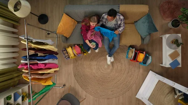Shopping, leisure and lifestyle advertisement concept. Top view close up shot of man and girl on the couch in the living room holding smartphone, showing new clothes to friends by video call.