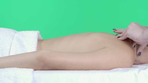 ボディトーナス広告コンセプト ビューティクリニックルーム マッサージテーブルに横たわる女性 クロマキーグリーンスクリーン背景 アクティブマッサージを行うマッサージ師 クローズアップ 広告エリア ワークスペースモックアップ — ストック動画