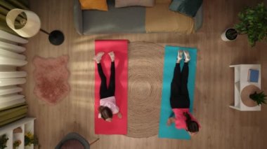 Kadın ve çocuk spor paspasları üzerinde durur ve egzersiz yapar, ısınırlar. Anne bacaklarını açarak esnetir, kız kendini şımartır. Tatbikatı bitirdiklerinde otururlar..