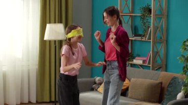 Çerçevede, bir anne ve kızı bir odada dikiliyorlar. Kızın gözleri bağlı ve göz bağıyla oynuyormuş gibi yapıyor. Kız, annesini yakalamaya çalışıyor. Sonra dokunur ve sarılırlar..