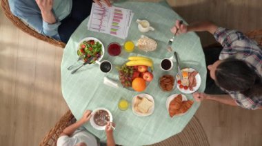 Aile ilişkileri ve ebeveynlik yaratıcı konsepti. Oturma odasında sabah oldu. Üst düzey aile kahvaltısı yiyor, anne akıllı telefondan evrak okuyor, babayı görmezden geliyor ve ilgi istiyor..