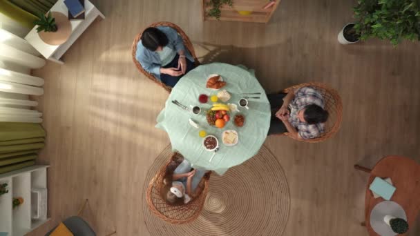 家族関係と親のクリエイティブコンセプト リビングでの朝 部屋のテーブルに座って朝食前に祈っている母親 小さな娘 父親のトップビュー — ストック動画
