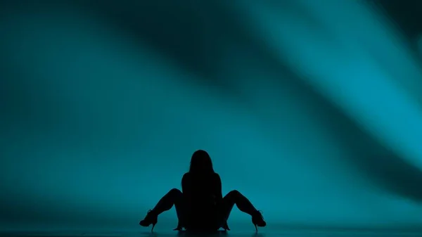 女人的轮廓在演播室里跳舞 明亮的青色 明亮的 阴影般的背景 黑色性感服装 高跟鞋 现代感官舞蹈编排 全身而退促销短片或广告 — 图库照片