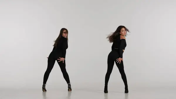スタジオで踊る2人の女性 明白な白い隔離された背景 ブラックセクシーな衣装 ハイヒール 現代のセンセーショナルな振付 全長について プロモーションクリップや広告 — ストック写真