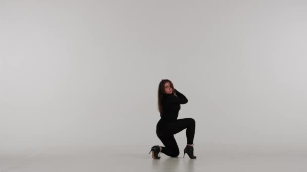 スタジオで踊る魅力的な女性 明白な白い隔離された背景 ブラックセクシーな衣装 ハイヒール 現代のセンセーショナルな振付 全長について プロモーションクリップや広告 — ストック動画