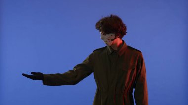 Beyaz maskeli bir adam mavi arka planda kırmızı ışıklı elini işaret ediyor. 13. Cuma 'dan manyak Jason Voorhees' in resmi. Çalışma alanı, reklam. Cadılar Bayramı konsepti.
