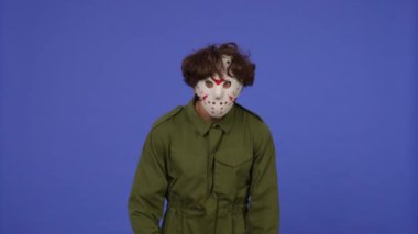 Mavi arka planda elinde testere olan beyaz maskeli bir adam. 13. Cuma 'dan manyak Jason Voorhees' in resmi. Cadılar Bayramı konsepti