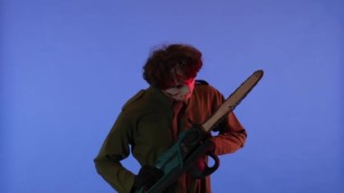 Beyaz maskeli, elinde testereyle mavi arka planda kırmızı ışıklı bir adam. 13. Cuma 'daki Jason Voorhees manyağı. Cadılar Bayramı konsepti.