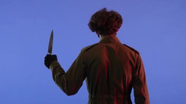 Mavi arka planda büyük, keskin bıçaklı, kırmızı ışıklı bir adam. 13. Cuma 'daki Jason Voorhees manyağı. Arkadan bak. Cadılar Bayramı konsepti.
