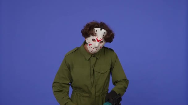 青い背景にチェーンソーと白いマスクの男 金曜日の13からのマニアックジェイソン ヴァイヘイズのイメージ ハロウィーンのお祝いのコンセプト — ストック動画