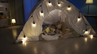 Baba ve oğul renkli kalemlerle resim çiziyorlar. Bir adam tapınakta bir çocuğu öpüyor. Baba ve oğul oturma odasındaki çelenk çadırında göbeklerinin üstünde yatıyorlar. Video 2 in 1 HDR BT2020 HLG