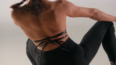 Modern dans stili yaratıcı reklam konsepti. Kadın dansçı portresi. Deri sutyen giyen kadın stüdyoda fevkalade pozlar veriyor, yakın çekim. Beyaz arkaplanda izole.